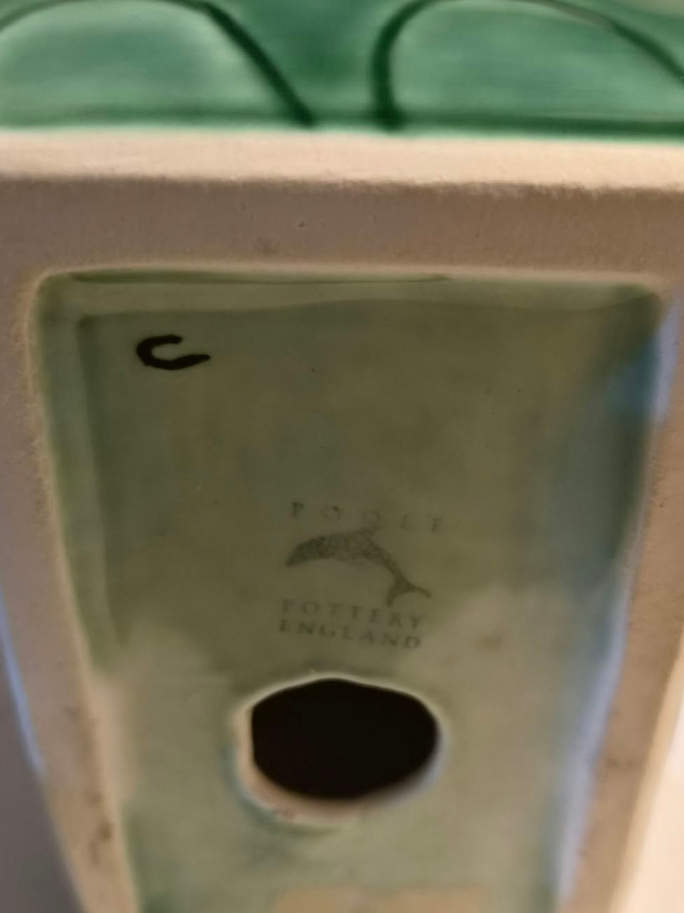 Underside of the green Poole Pottery elephant bookend showing the dolphin factory mark and handwritten C
