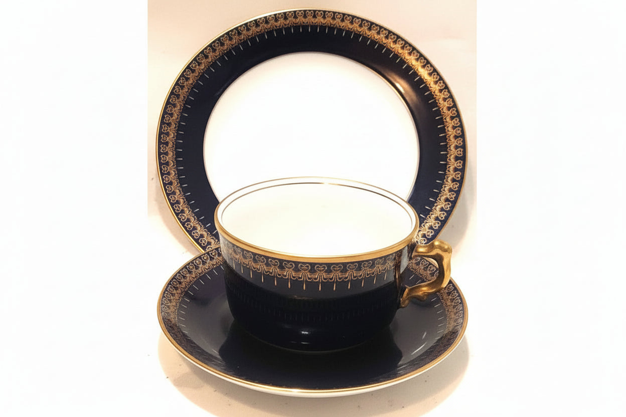Black teacup and saucer with gold detailing on a white background