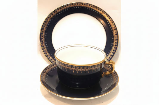 Black teacup and saucer with gold detailing on a white background