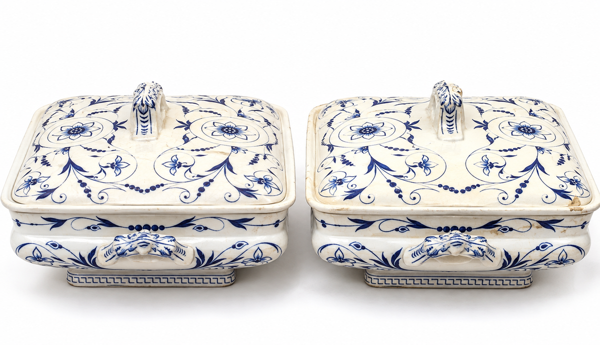 A pair of vintage blue and white porcelain lidded boxes with ornate floral patterns and decorative handles, set against a plain white background.