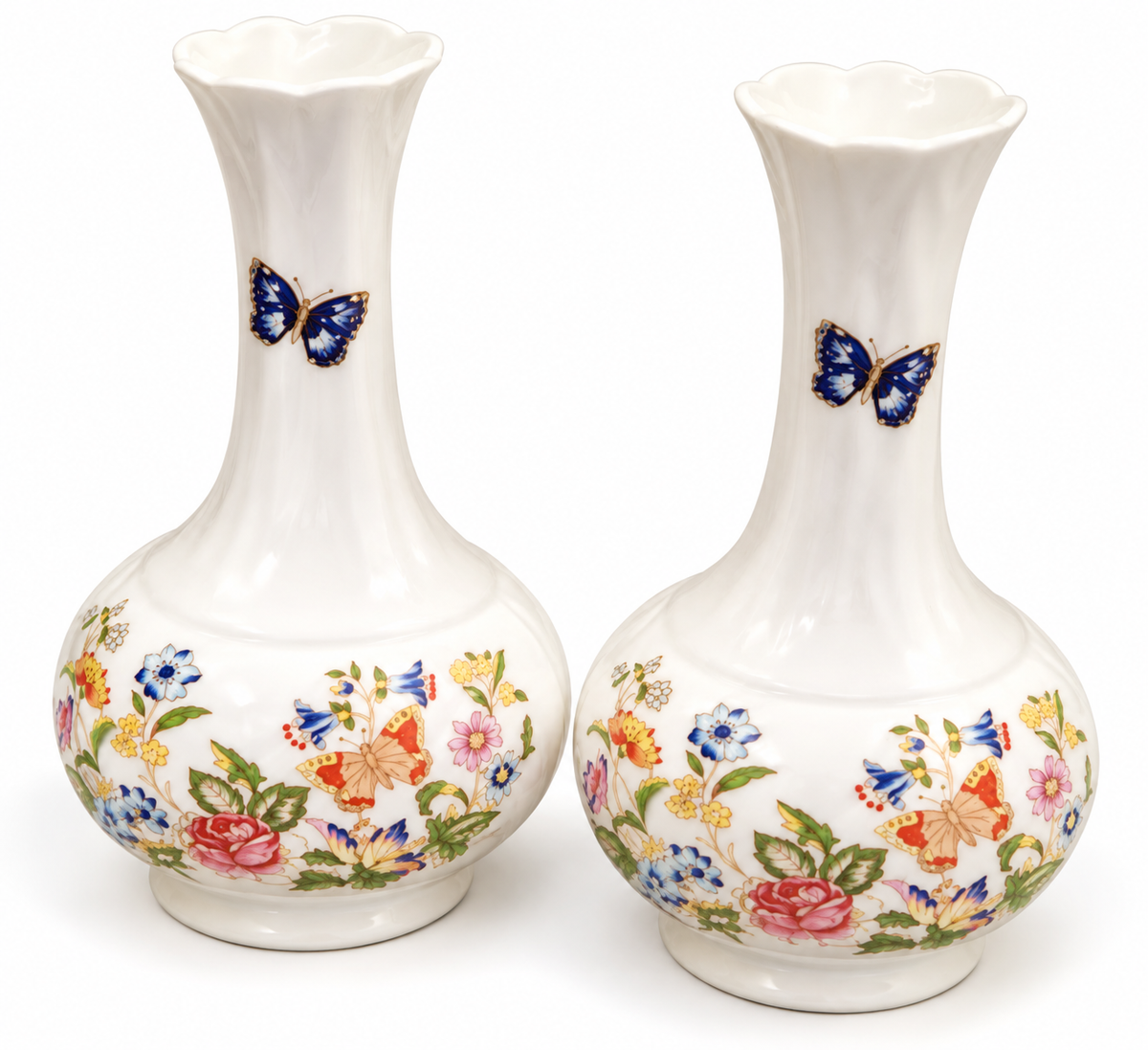 A pair of white ceramic budvases with a fluted neck and a colorful floral and butterfly pattern on the lower body, set against a plain white background.