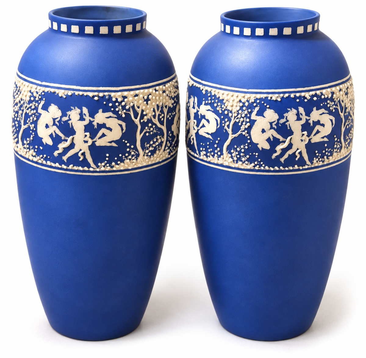 A pair of cobalt blue ceramic vases with cream-colored decorative bands depicting classical figures and trees, set against a plain white background.