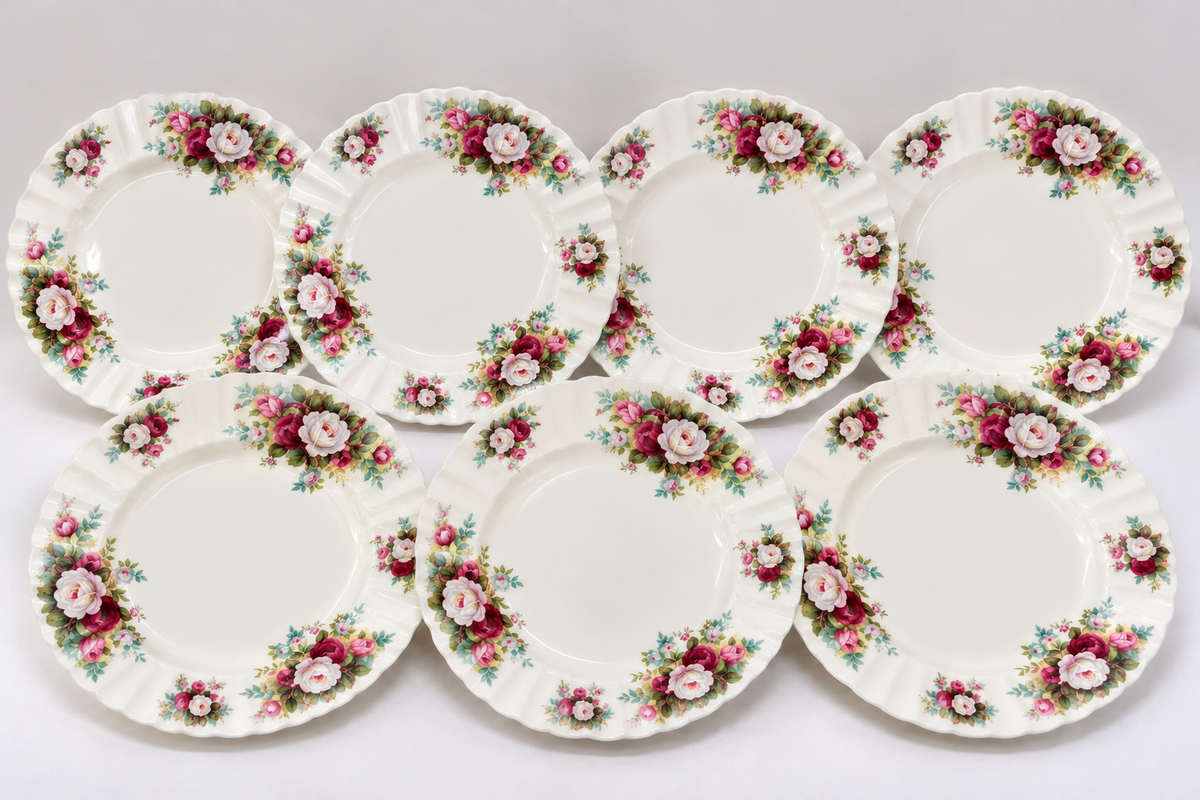 Six vintage ceramic plates with a classic floral border pattern, arranged in two rows of three on a light gray background.