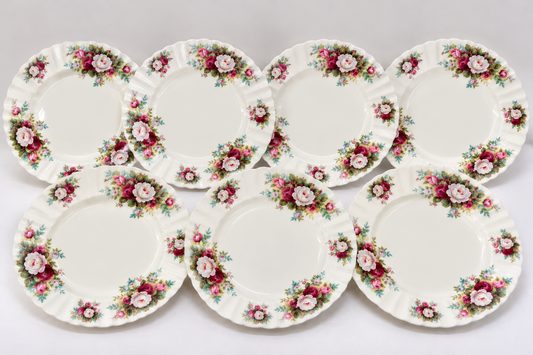 Six vintage ceramic plates with a classic floral border pattern, arranged in two rows of three on a light gray background.