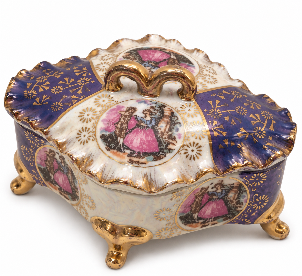 An ornate porcelain lidded box with a decorative lid, featuring a deep cobalt blue and white enamel pattern, gold gilding, and hand-painted pink and multicolor scenes of women in historical dress.